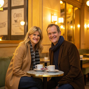 Imogen Stubbs and Alexander Armstrong, smiling for the camera in a cozy cafe. Warm, golden lighting, casual outfits