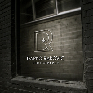 Modern, sleek logo for Darko Rakovic Photography. The logo features a stylized 'R' with a small star-like symbol above it. Monochromatic color scheme. Text clearly indicates photography service.
