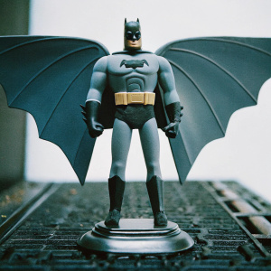 Batman Beyond Warhawk action figure standing on sleek metallic base. Confident pose, muscular build, menacing expression, gray and black costume, distinctive belt, large wing-like appendages. Against stark white backdrop.
