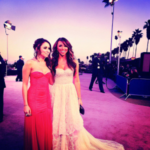 Miley Cyrus and her mother Leticia 'Tish' Cyrus walking the Golden Globe Awards red carpet. Wearing a glamorous white lace gown and a chic red dress. Backdrop of flashing cameras and celebrities