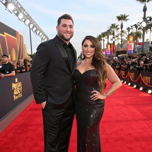Chris Buckner and Deena Nicole Cortese, in glamorous evening attire, on the vibrant red carpet at the 2019 MTV Movie and TV Awards. Festive atmosphere with flashing cameras and fans.
