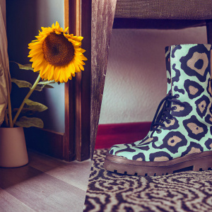 Tyler The Creator's 'Flower Boy' album cover featuring a mix of black and white abstract art, a sunflower, and a boot. Bold shapes and contrasting imagery.
