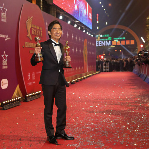 Tony Leung Chiu-wai, Asian actor, standing confidently with awards. Glittering red carpet event, vibrant backdrop, industry logos