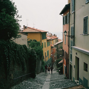 Streets of Menton, French Riviera. Vibrant pastel-colored buildings and narrow cobblestone streets winding up the hillside. Traditional architecture and bustling atmosphere.