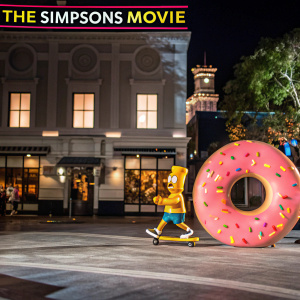 Promotional image for 'The Simpsons Movie'. Bart Simpson and Homer Simpson are seen skateboarding and hugging respectively. Pink doughnut in foreground. White backdrop