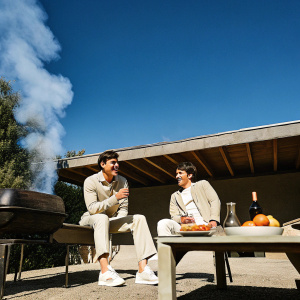 Max Verstappen and Charles Leclerc in a candid photo, both in casual wear. Backyard barbecue setting.