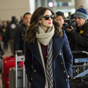 Actress Emmy Rossum, wearing a stylish winter coat, scarf, and sunglasses. Surrounded by fans and paparazzi at LAX airport.