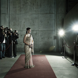 Kajol Devgan gracing the premiere of a new film. Red carpet scene. Traditional attire - an intricate gold and pink saree paired with matching jewelry. Crowds and photographers capturing the moment.