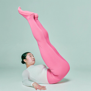 Lee Eun Ju, East Asian gymnast, in an intense pose at a sports hall. White undershirt and red leotard. Dark background highlights her athletic form. High contrast photo.