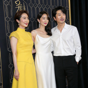 Lee Da-Hee, Lee Bo-Young, and Yoon Sang-Hyun at a glamorous Hollywood premiere. Wearing a vibrant yellow dress, a sleek white dress, and a classic white shirt. A sleek black backdrop with intricate gold details. No special effects.