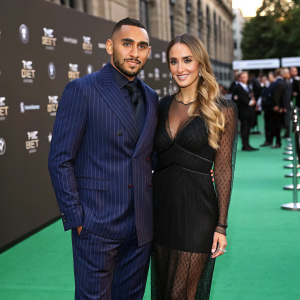 Dimitri Payet and Ludivine Payet on the green carpet for The Best FIFA Football Awards 2022. Dimitri in dark blue pinstripe suit, Ludivine in black sheer dress.