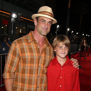 Christopher Meloni, donning a brown and orange plaid shirt and a beige fedora, alongside his younger lookalike Dante Amadeo Meloni, who sports a red shirt. The pair graces the premiere with their presence.