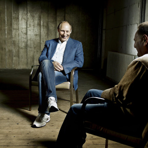Vladimir Putin, Russian president, in a casual meeting. Wearing blue blazer, jeans, and sneakers. Smiling broadly.
