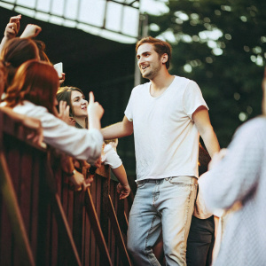 Kendall Schmidt at a casual meet and greet event. Wearing a white t-shirt and jeans. Fans surrounding him.