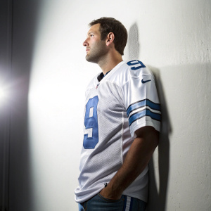 Tony Romo wearing Dallas Cowboys jersey with number 9. Stark white background, spotlight