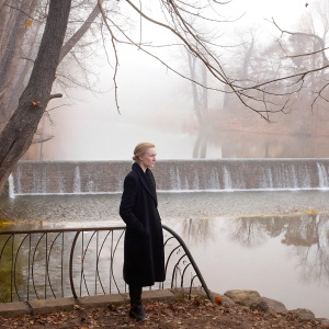 Evan Rachel Wood, blonde hair, outdoors near waterfall. Wearing black coat. Thoughtful pose.
