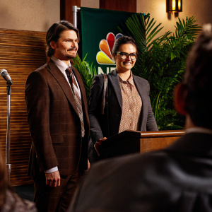Jason Ritter and Marianna Palka at a press conference for their new NBC show. They are dressed in formal attire with the NBC logo backdrop behind them.