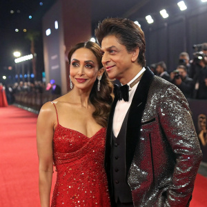 Shahrukh Khan and Malaika Arora at a glamorous award show. Sparkling costumes and red carpet backdrop.