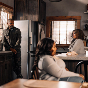 A still from S.W.A.T. featuring Shemar Moore, Deshae Frost, and Debbie Allen. Warm kitchen setting with earthy tones, appliances visible, actors in character poses.