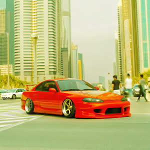 A custom Nissan Silvia S15, with a sleek and aerodynamic design, parked on a bustling city street with tall skyscrapers in the background.