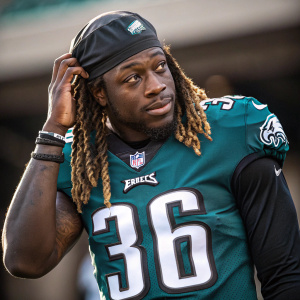 Jay Ajayi, from the Philadelphia Eagles, posing with his number 36 jersey. Close-up shot, long hair styled in braids. The background is blurred.