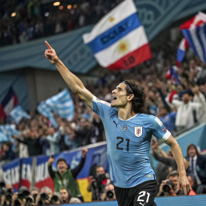 Edinson Cavani, wearing a blue jersey with the number 21, is celebrating a goal. Stadium filled with excited fans cheering.