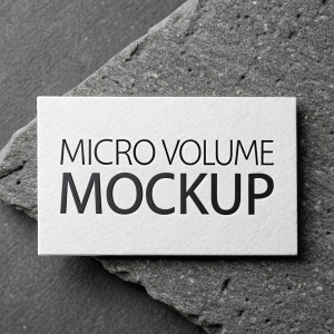 Digital design showcasing a sleek business card layout. 'Micro Volume Mockup' written in bold black letters. Placed on a rough, grey granite surface.