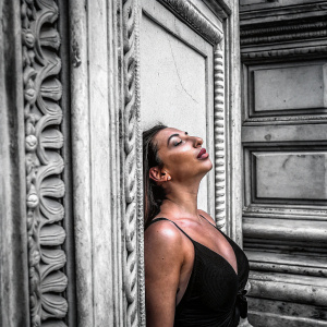 Close-up portrait of Stassi Schroeder, dressed in a black halter top. Ornate grey wall backdrop