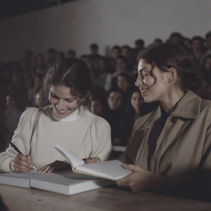 Laetitia Casta and Audrey Dana at a lively book signing event. Crowded room with diverse crowd. Blurred background