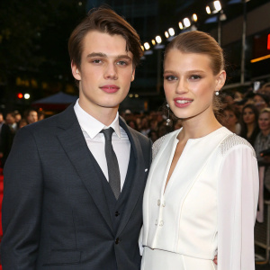 Nicholas Galitzine and Keenan Kampa at the film premiere. Wearing formal attire. Dark grey suit and white blouse. Crowd in background.