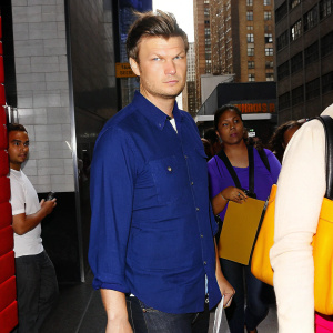 Nick Carter, with a stern expression, in a casual blue denim shirt. Midday on a busy street.