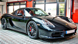 A porsche 918 spyder black in a garage , car on right side of image