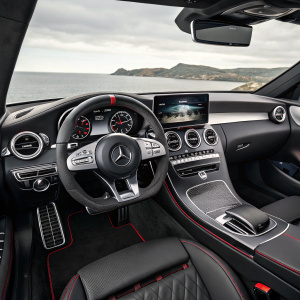 Inside a sleek 2021 Mercedes-Benz C63 AMG Coupe, the modern interior features a black dashboard with silver and red accents. The steering wheel, center console, and display screens blend seamlessly in a monochromatic theme.