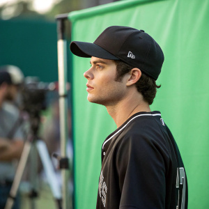 Actor Dylan O'Brien on set, wearing a black cap and a jersey. Green screen environment