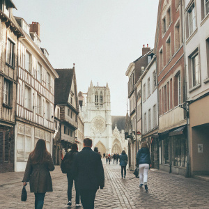 In the heart of a bustling town, cobblestone streets stretch out, lined with charming half-timbered buildings and bustling shops. The backdrop features the grand Saint Martin's Cathedral, standing tall with its distinctive architecture, creating a lively scene.