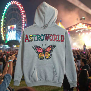 Travis Scott's Astroworld merchandise includes a grey hoodie with 'ASTROWORLD' logo in bold letters and butterfly design. Music festival scene