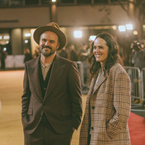 Carlos Leal and Jo Kelly at the 'The L Word: Generation Q' premiere. Red carpet event. Carlos in brown hat and dark attire, Jo in plaid jacket.