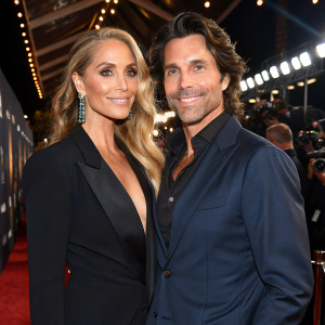 Elizabeth Berkley and Greg Lauren at a glamorous award show. Elizabeth in a bold black dress. Greg in a navy suit. Both smiling