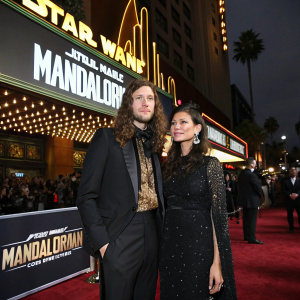 Ludwig Goransson and Serena McKinney attending 'The Mandalorian' premiere. El Capitan Theatre, Hollywood. Wearing formal attire, against Star Wars-themed backdrop.