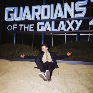 Wyatt Oleff, young actor, attending Guardians of the Galaxy Vol. 2 world premiere. Formal attire, smiling. Dark backdrop with neon movie title.