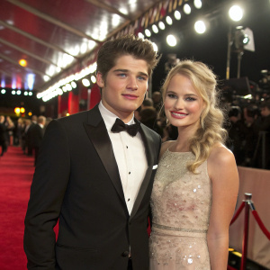 Gregg Sulkin and Brittany Robertson attending a glitzy awards ceremony. Formal attire, glamorous backdrop.