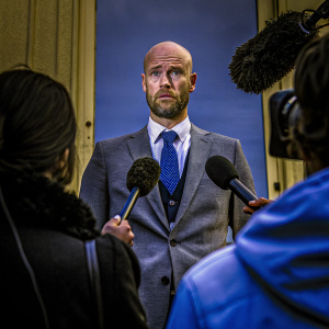 Erik Ten Hag, Manchester United manager, at the post-match press conference. Intense expression, gray suit, blue tie.
