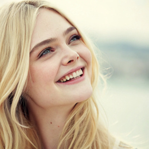 Elle Fanning, blonde actress, close-up smile. Soft focus, blurred background