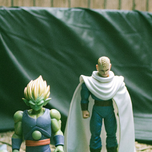 Collection of Dragon Ball action figures. Piccolo with green skin, Vegeta with white cape and blonde hair. Plain black backdrop