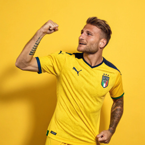 Ciro Immobile, soccer player, in a Puma jersey. Confident pose. Yellow background. Solid color