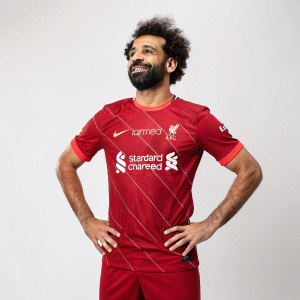 Mohamed Salah wearing a custom-designed jersey featuring 'Standard Chartered' sponsor logo. The shirt bears his name and Liverpool FC-inspired red uniform.