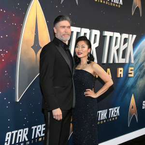 Anson Mount and Darah Trang at the premiere event. Star Trek-themed backdrop featuring the iconic ship and logo. Both dressed in elegant evening wear.