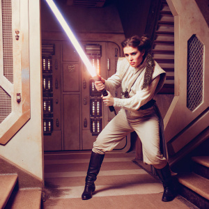 Padme Amidala, Star Wars character, wielding lightsaber in fierce battle stance. Futuristic space station background