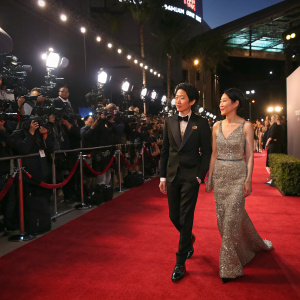 Takamasa Ishihara and Melody Ishihara at a glamorous awards show. Red carpet with flashing cameras.