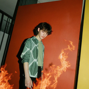Heatblast from Ben 10, fiery flames surrounding him. Green design on shirt. Bright yellow backdrop